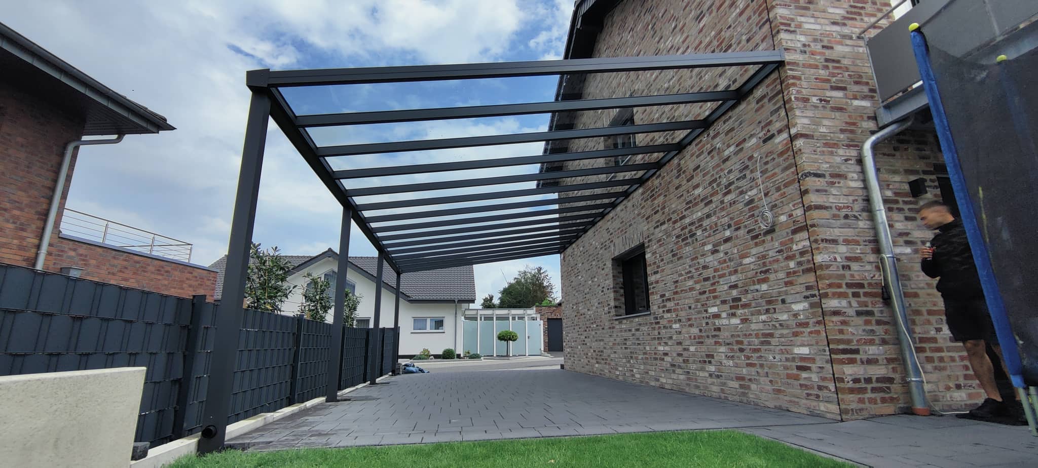 Pultdach-Carport aus Aluminium in Anthrazit mit Glaseindeckung am Klinkerhaus