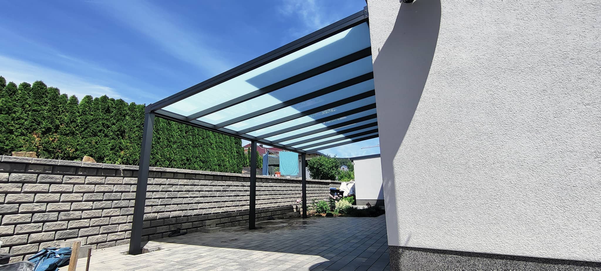 Carport aus Aluminium in Anthrazit mit Milchglas-Eindeckung neben dem Wohnhaus