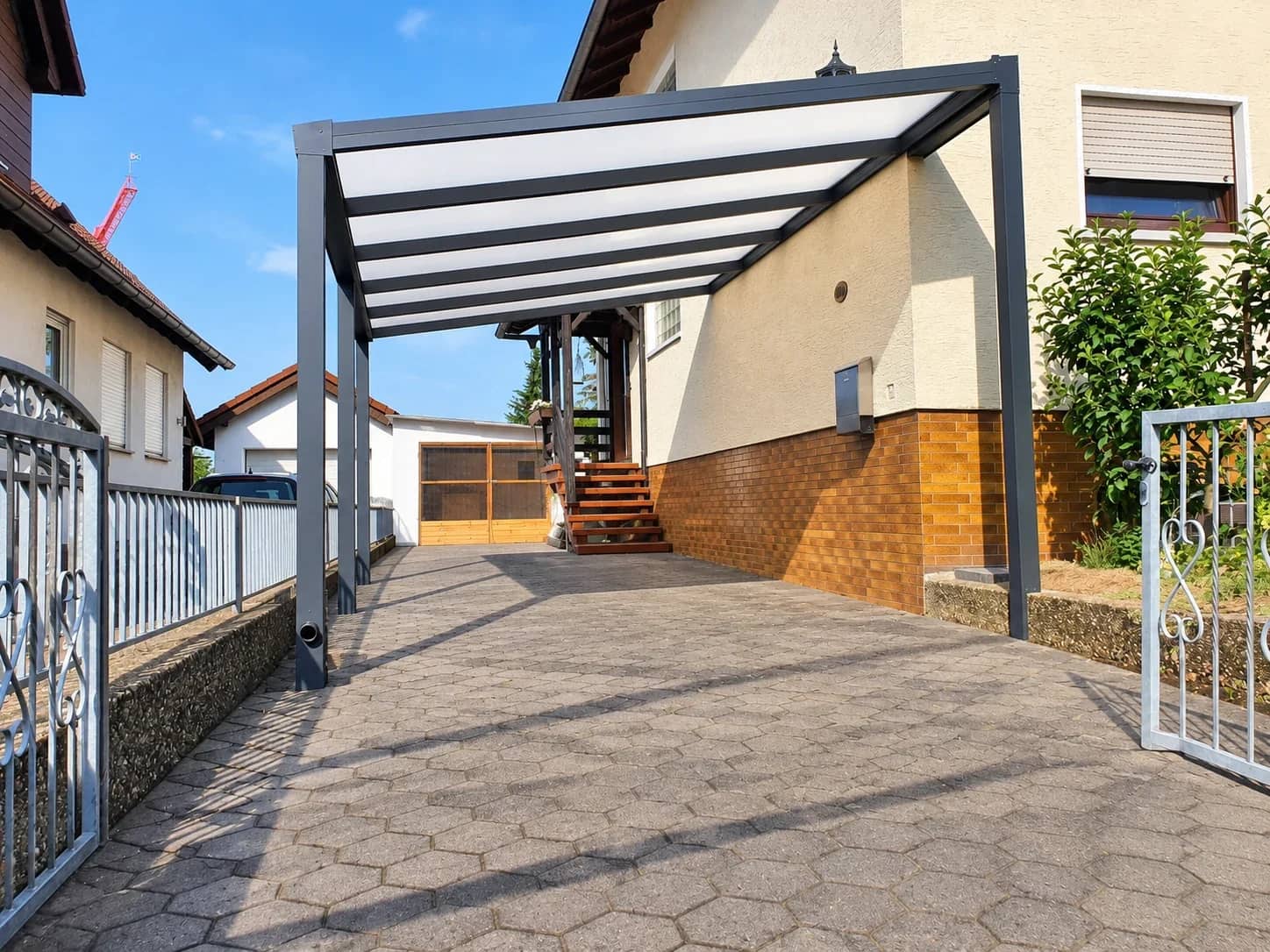 Carport aus Aluminium in Anthrazit – lichtdurchlässige Überdachung über gepflasterter Einfahrt