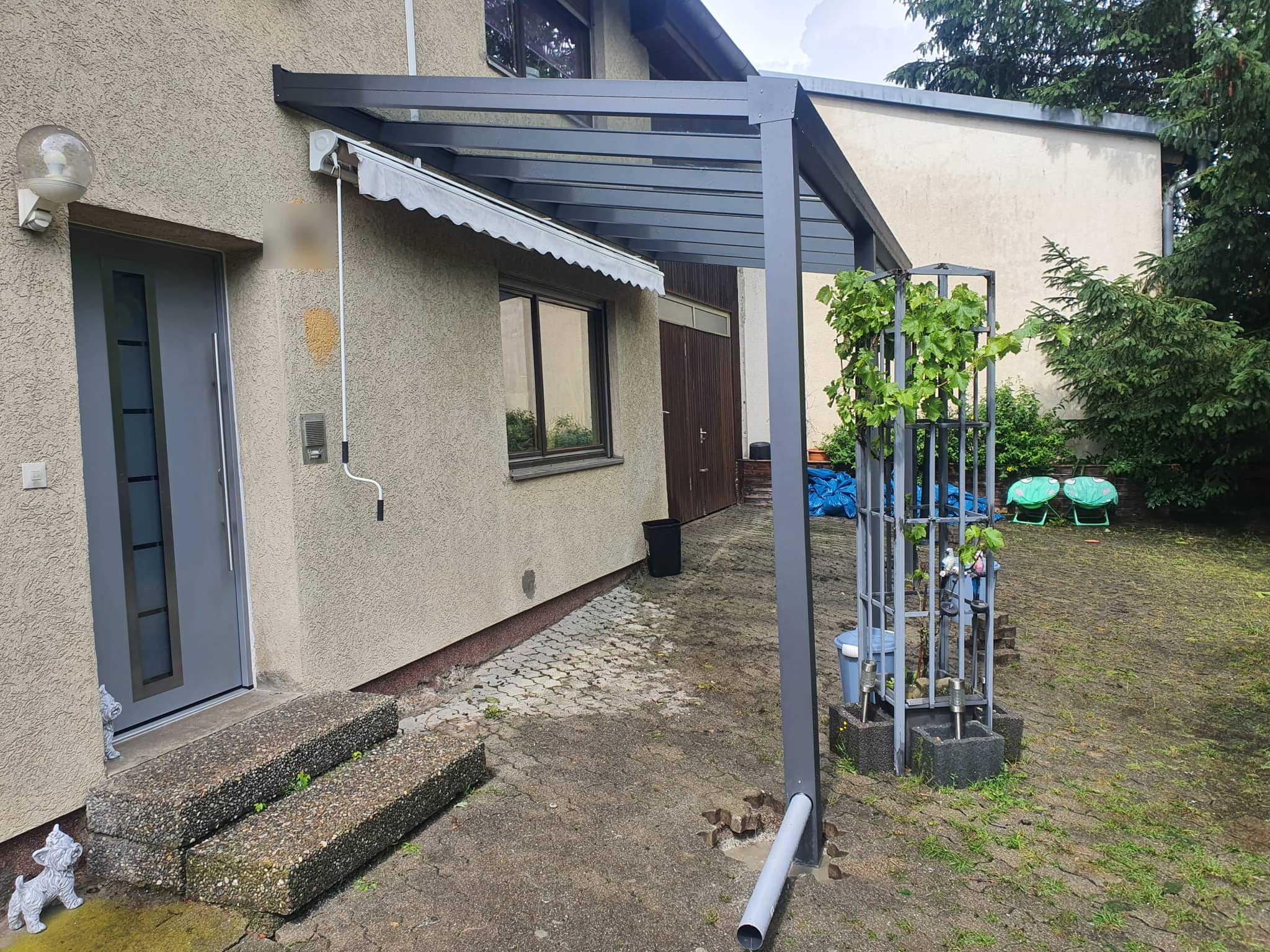 Eingangsüberdachung aus Aluminium in Anthrazit, wandmontiert entlang der Hausseite mit Stütze und lichtdurchlässiger Eindeckung