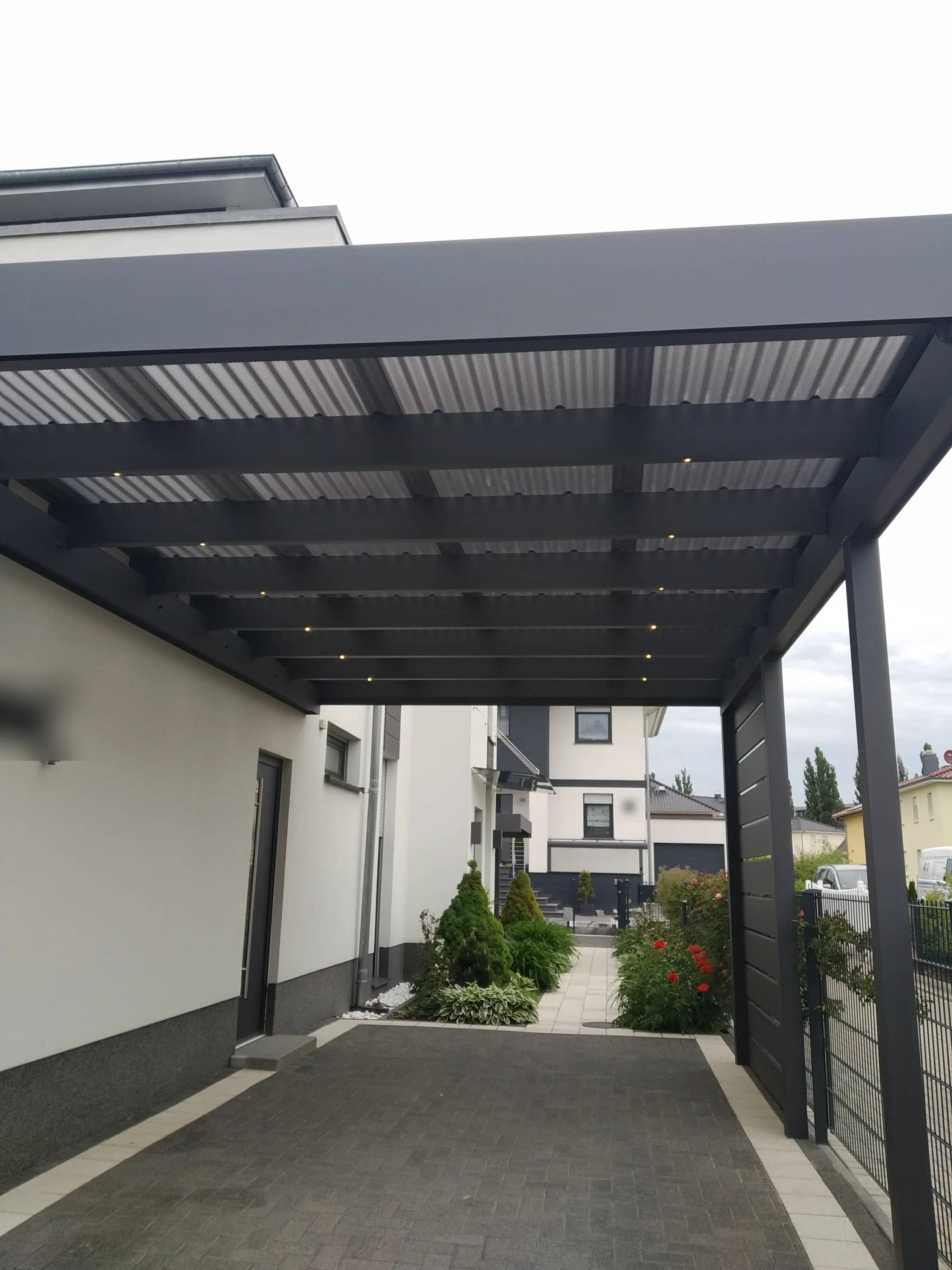 Flachdach-Carport aus Aluminium in Anthrazit an der Hauswand, Blick von unten auf Dachfläche und Stützen
