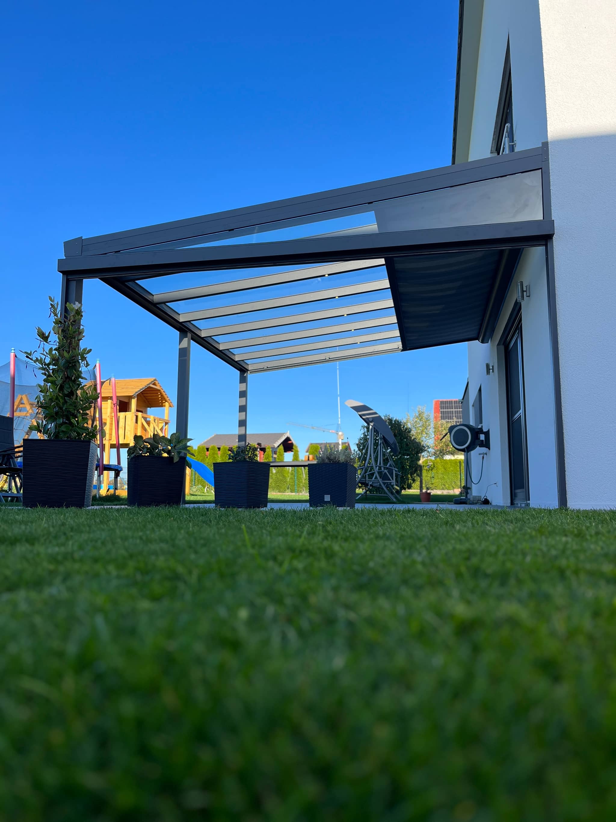 Aluminium-Terrassenüberdachung mit Unterglas-Beschattung an einem hellen Wohnhaus