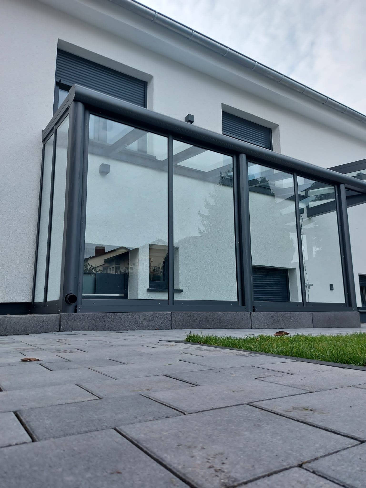 Sommergarten aus anthrazitfarbenem Aluminium mit festen Glaswänden am modernen Wohnhaus