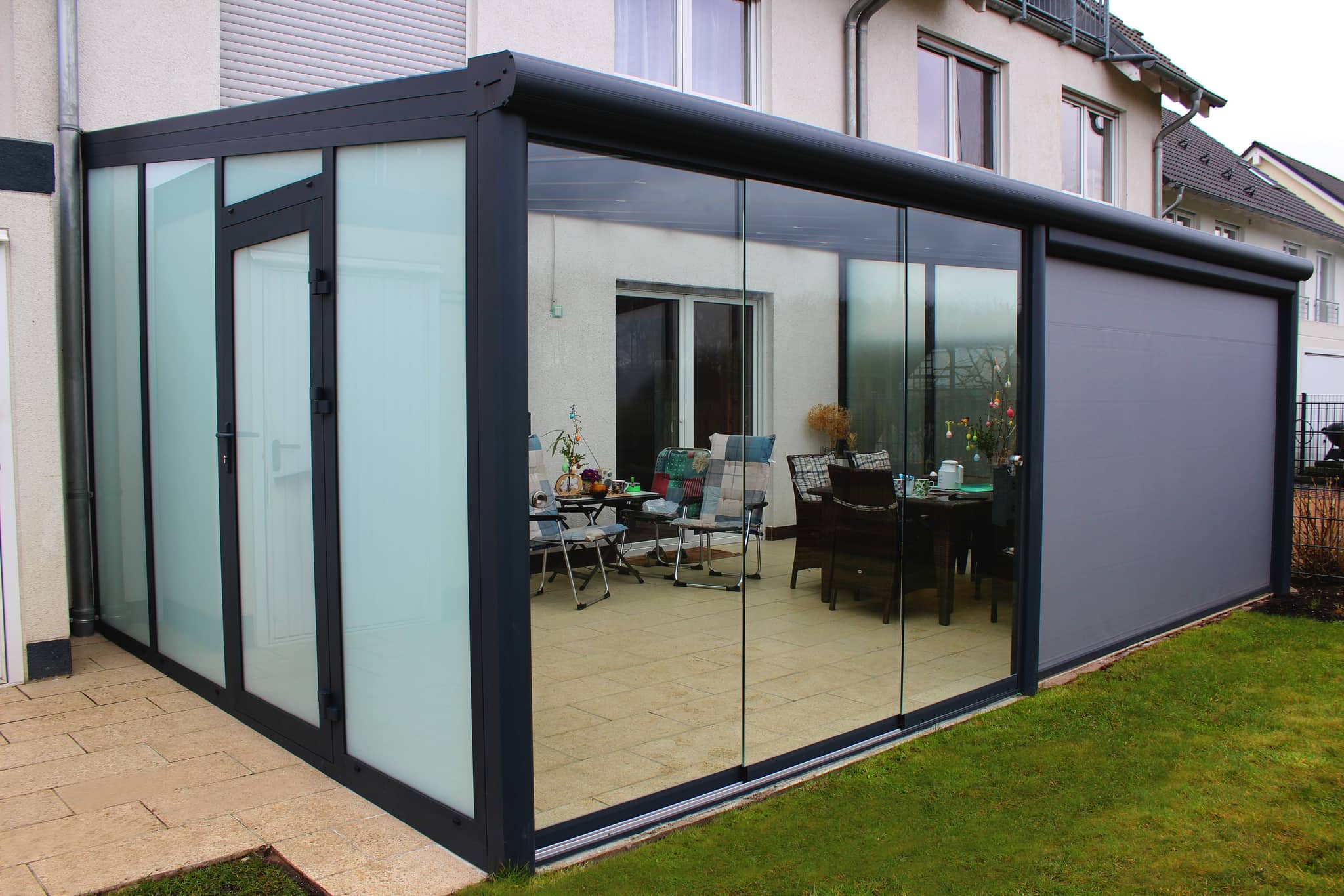 Sommergarten aus Aluminium in Anthrazit mit Glas-Schiebeelementen, Milchglas-Seitenwand und Panelwand am Wohnhaus