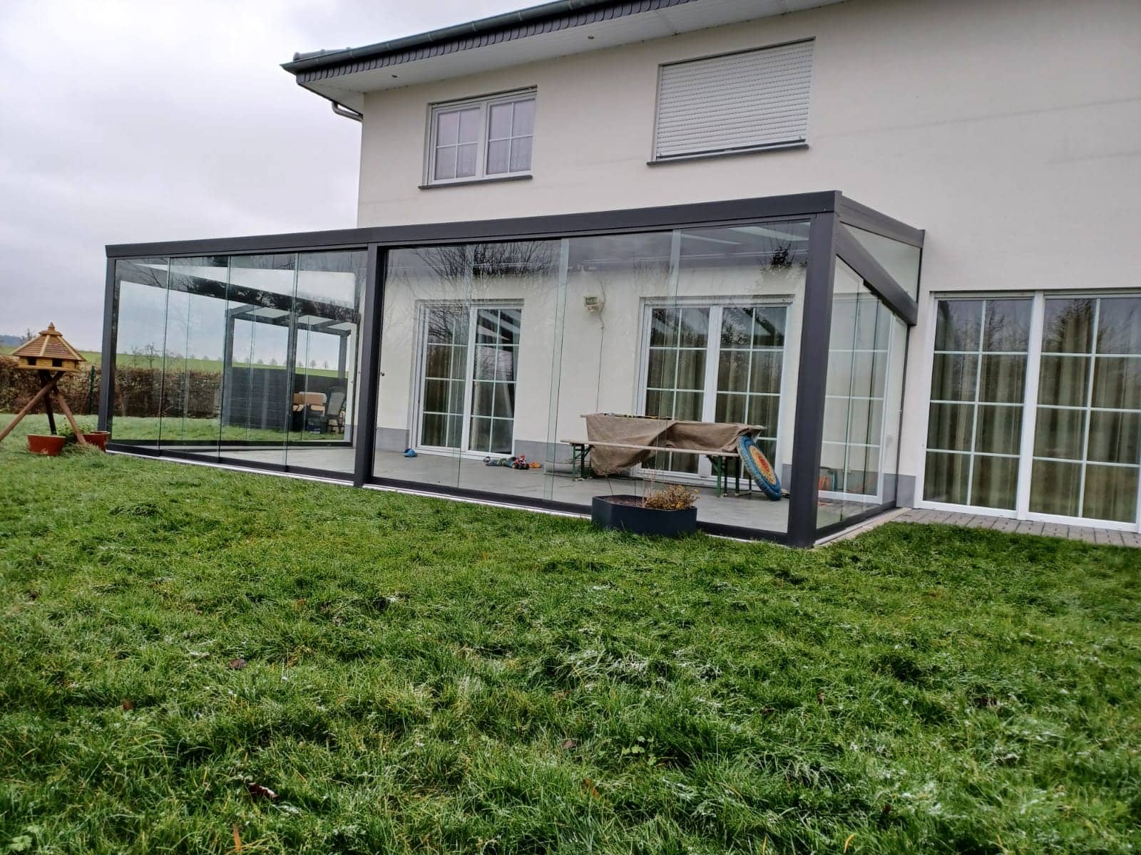 Sommergarten aus Aluminium mit umlaufender Verglasung an einem hellen Wohnhaus