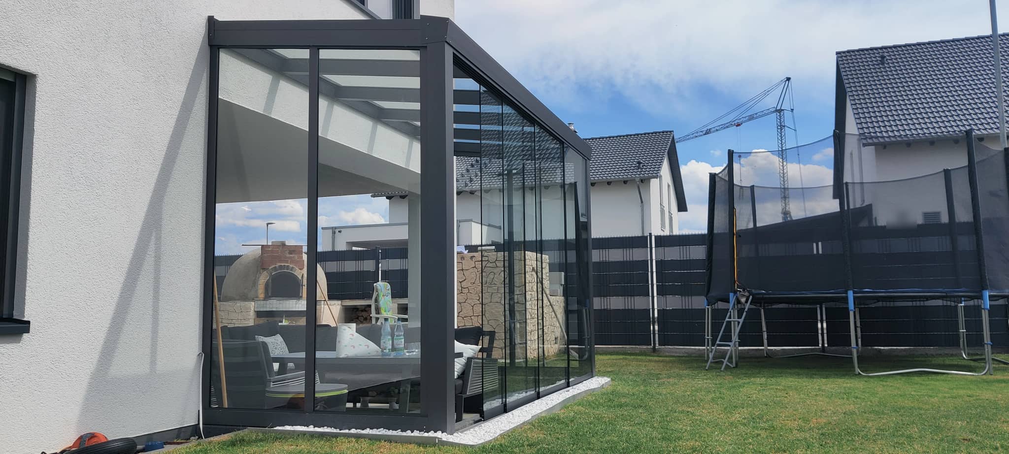 Sommergarten aus anthrazitfarbenem Aluminium mit umlaufender Verglasung, Wintergarten-Anbau am Wohnhaus mit freiem Blick in den Garten