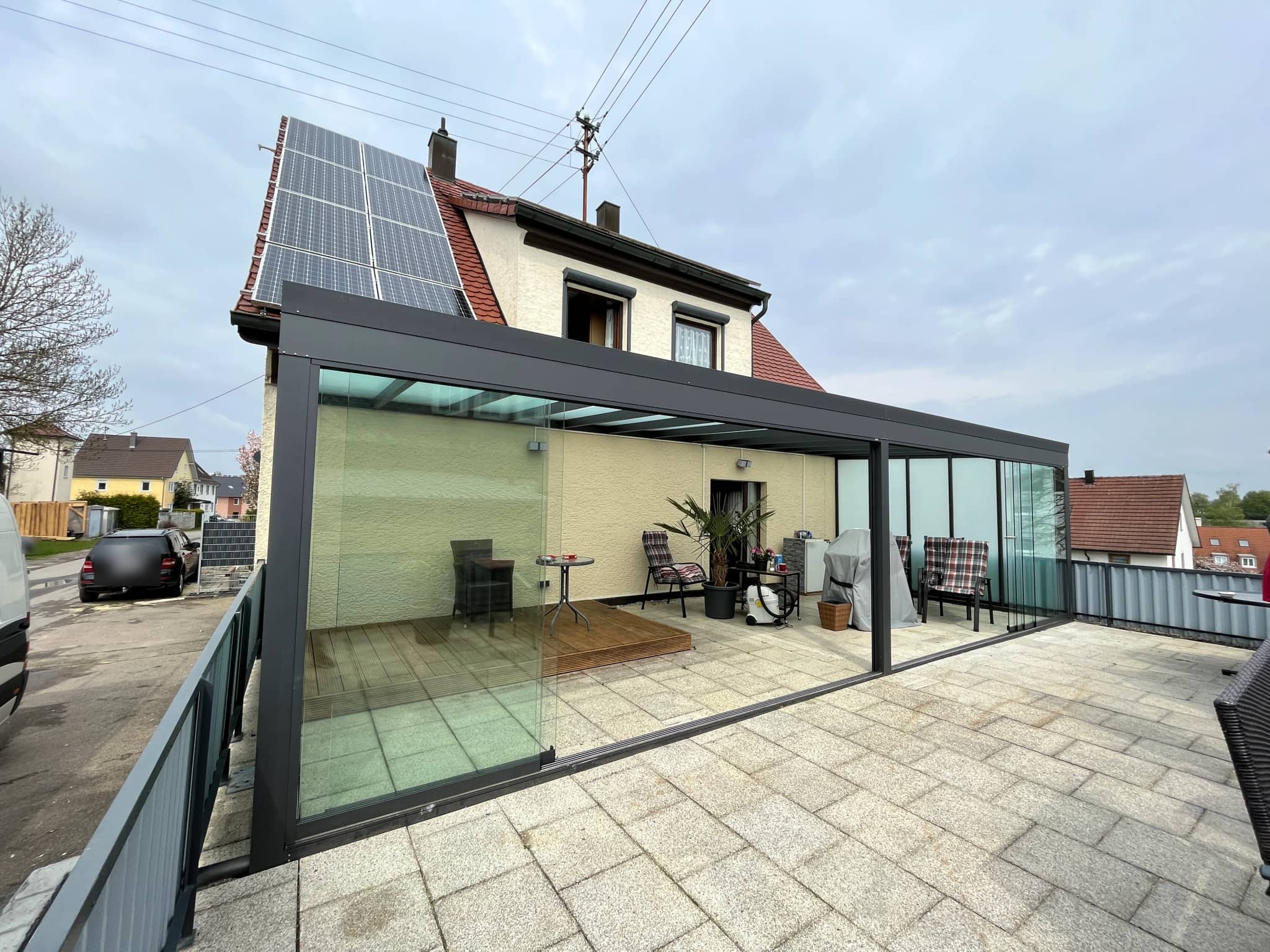 Sommergarten aus anthrazitfarbenem Aluminium mit Ganzglas-Schiebeelementen auf der Dachterrasse, lichtdurchlässige Eindeckung am Einfamilienhaus