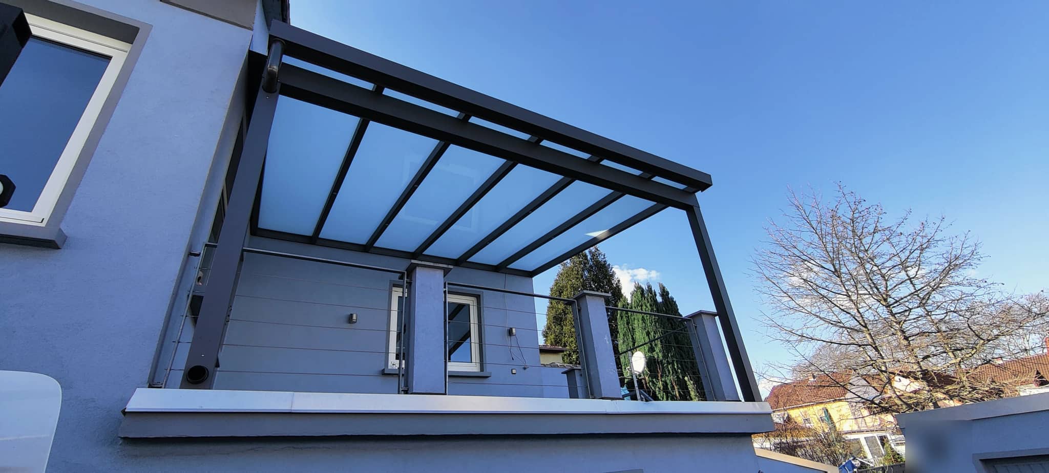 Untersicht eines Terrassendachs mit lichtdurchlässiger Eindeckung zwischen den Sparren gegen den Himmel