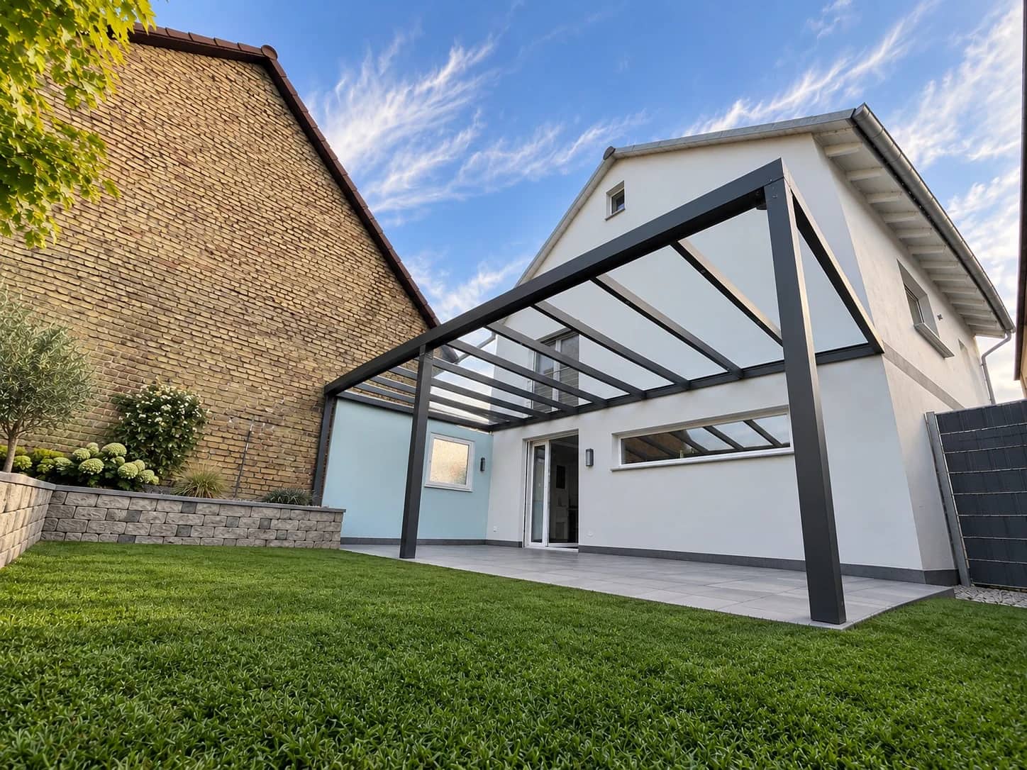 Terrassenüberdachung aus Aluminium in Anthrazit mit klarer Glaseindeckung an einem Einfamilienhaus