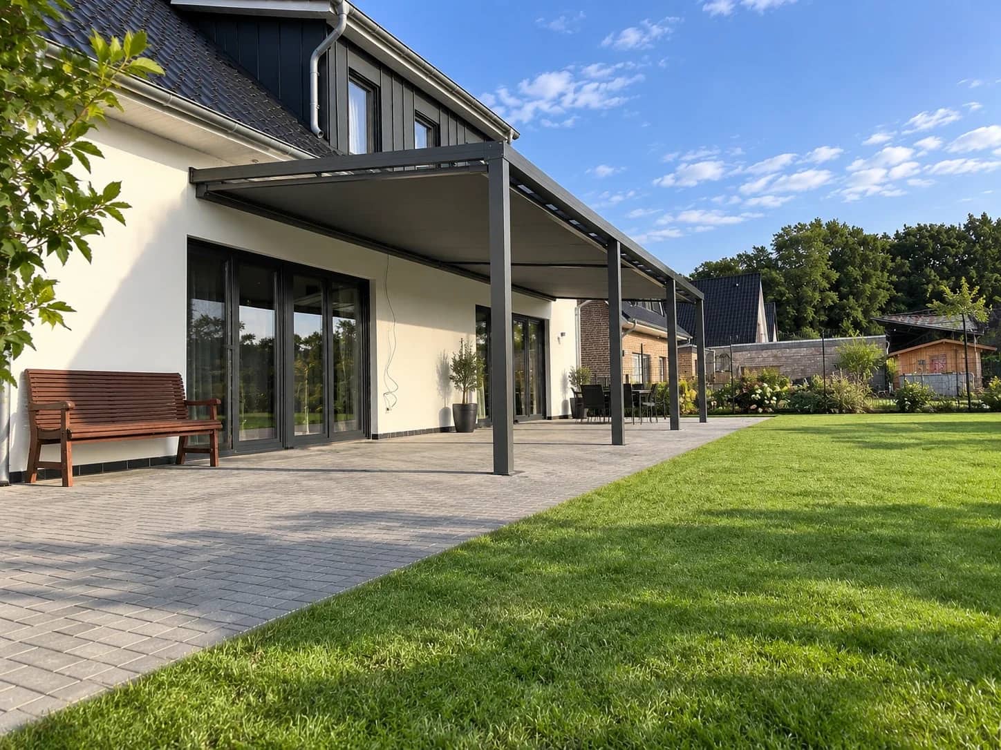Terrassenüberdachung aus Aluminium mit Glasdach und gekoppelter Markise entlang der Hausfront