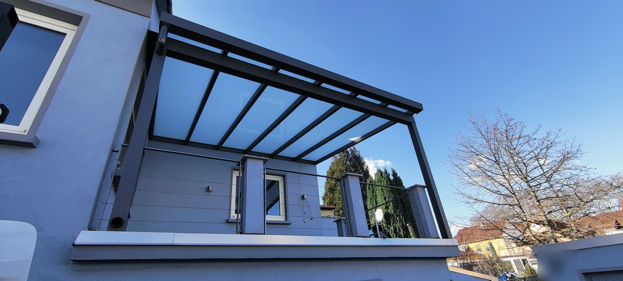 Untersicht eines Terrassendachs mit lichtdurchlässiger Eindeckung zwischen den Sparren gegen den Himmel