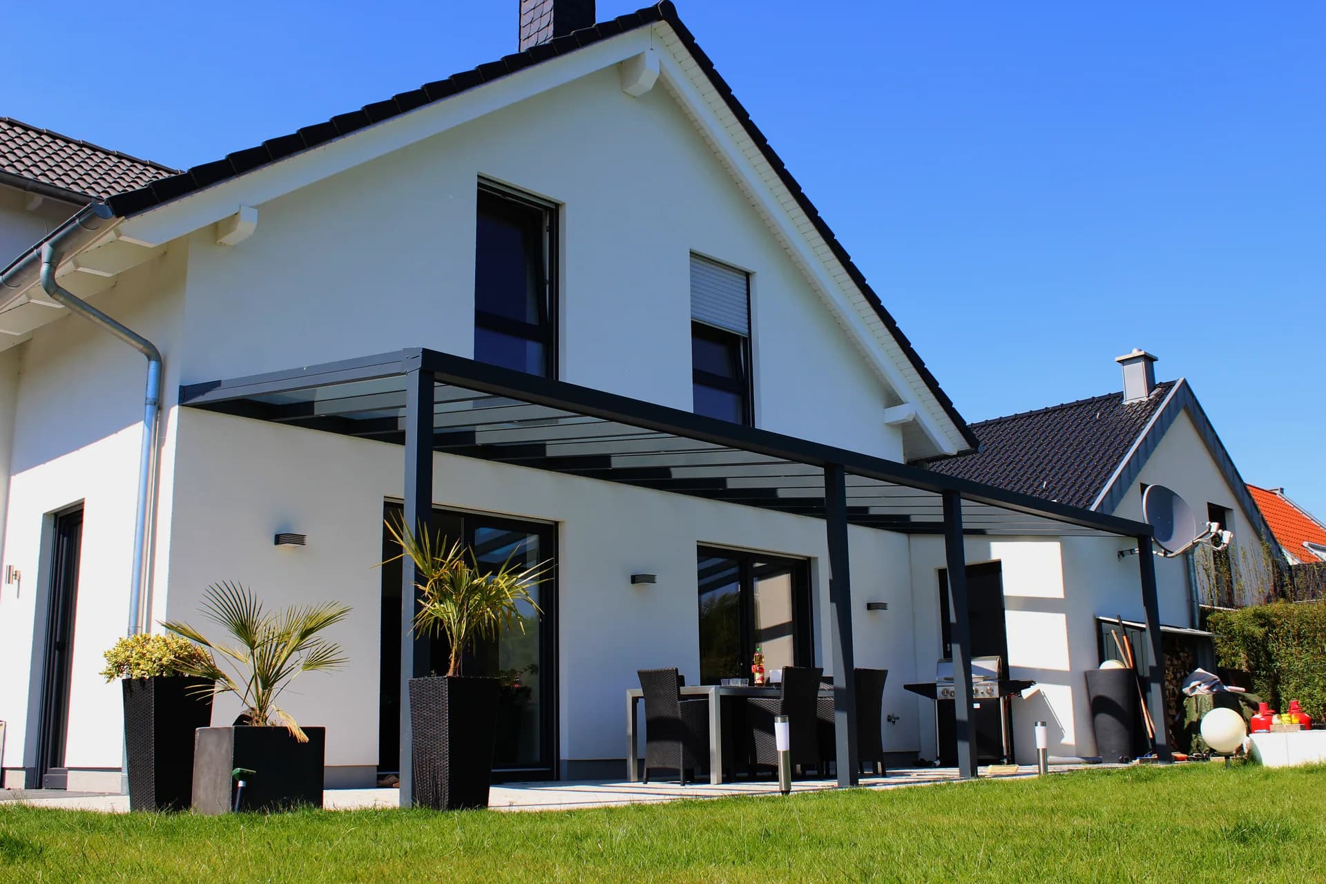 An das Wohnhaus angebaute Aluminium-Terrassenüberdachung mit lichtdurchlässigem Dach